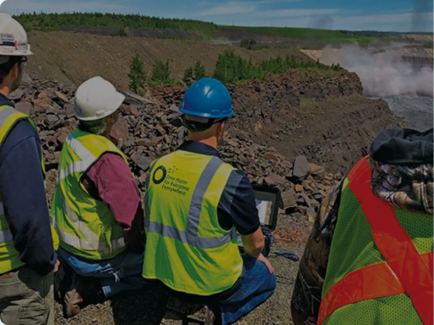 Site team overlooking an open mining pit